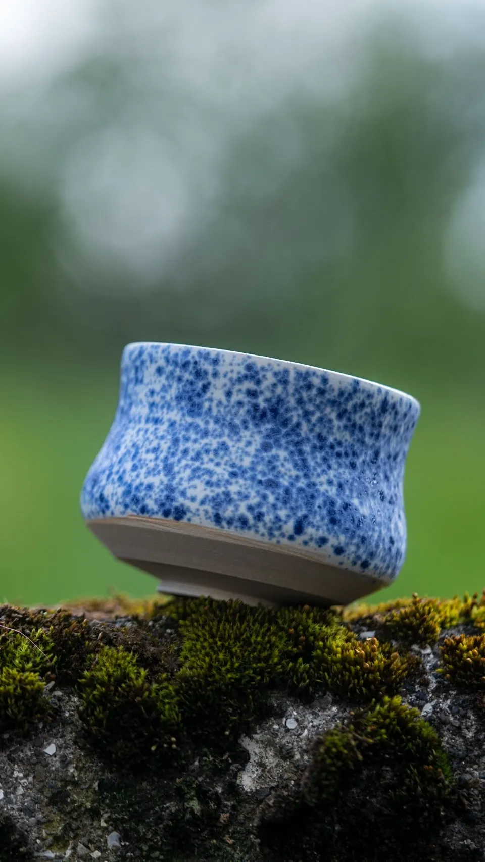 Teal and black speckled cup set into Icelandic moss
